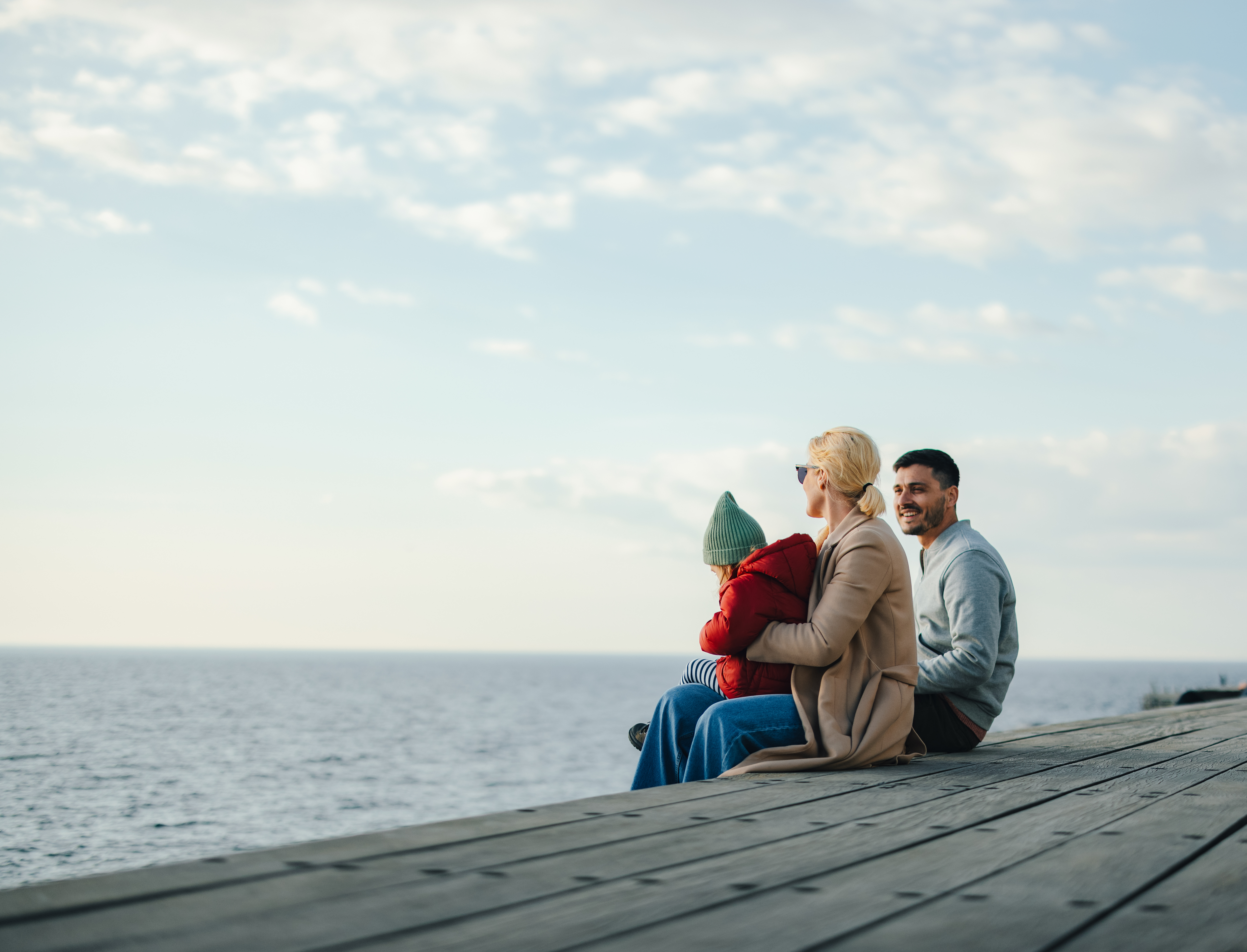 Family of three sitting on a dock