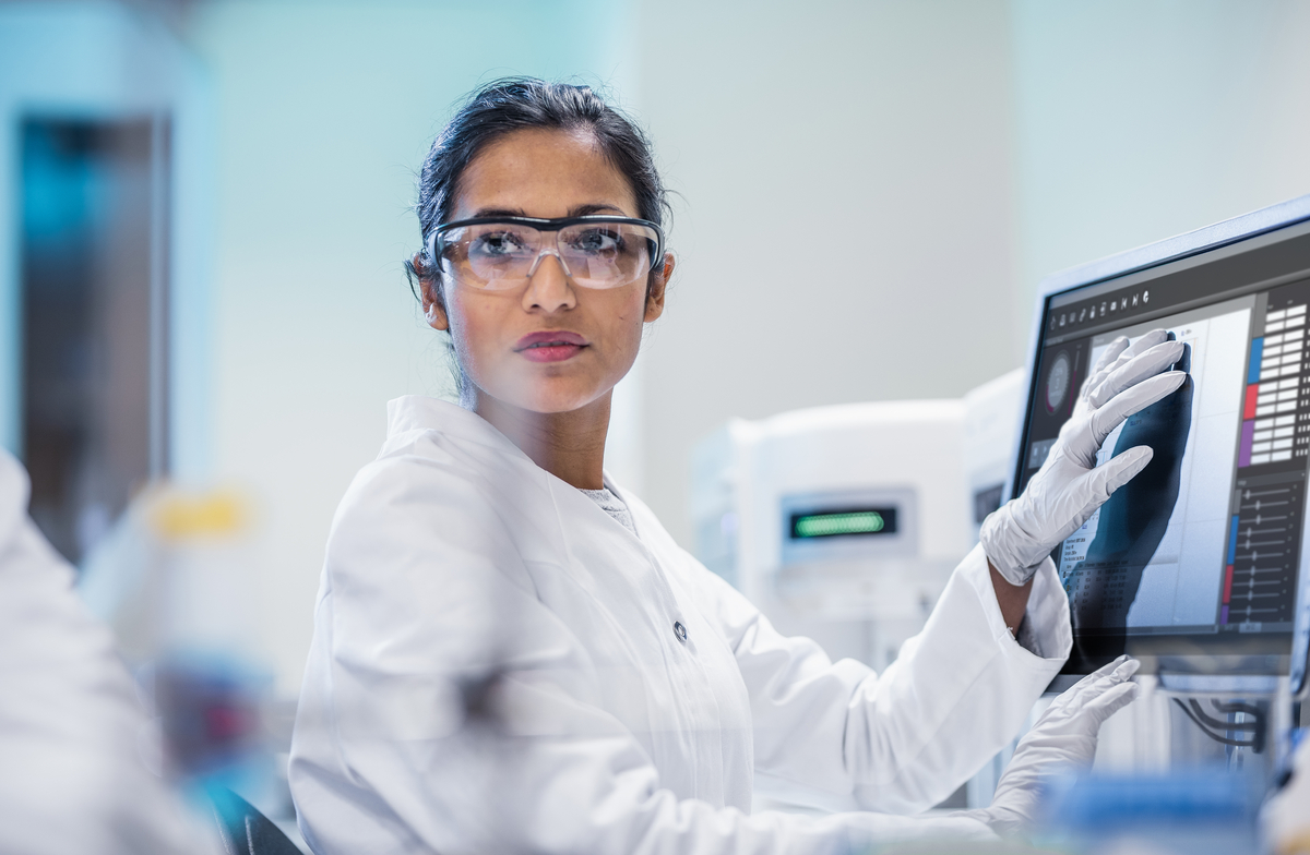 Scientist with her hand over a computer screen. She is looking off into the distance