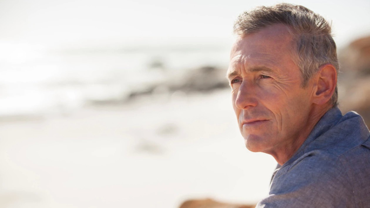 Middle aged man staring off into the distance outside