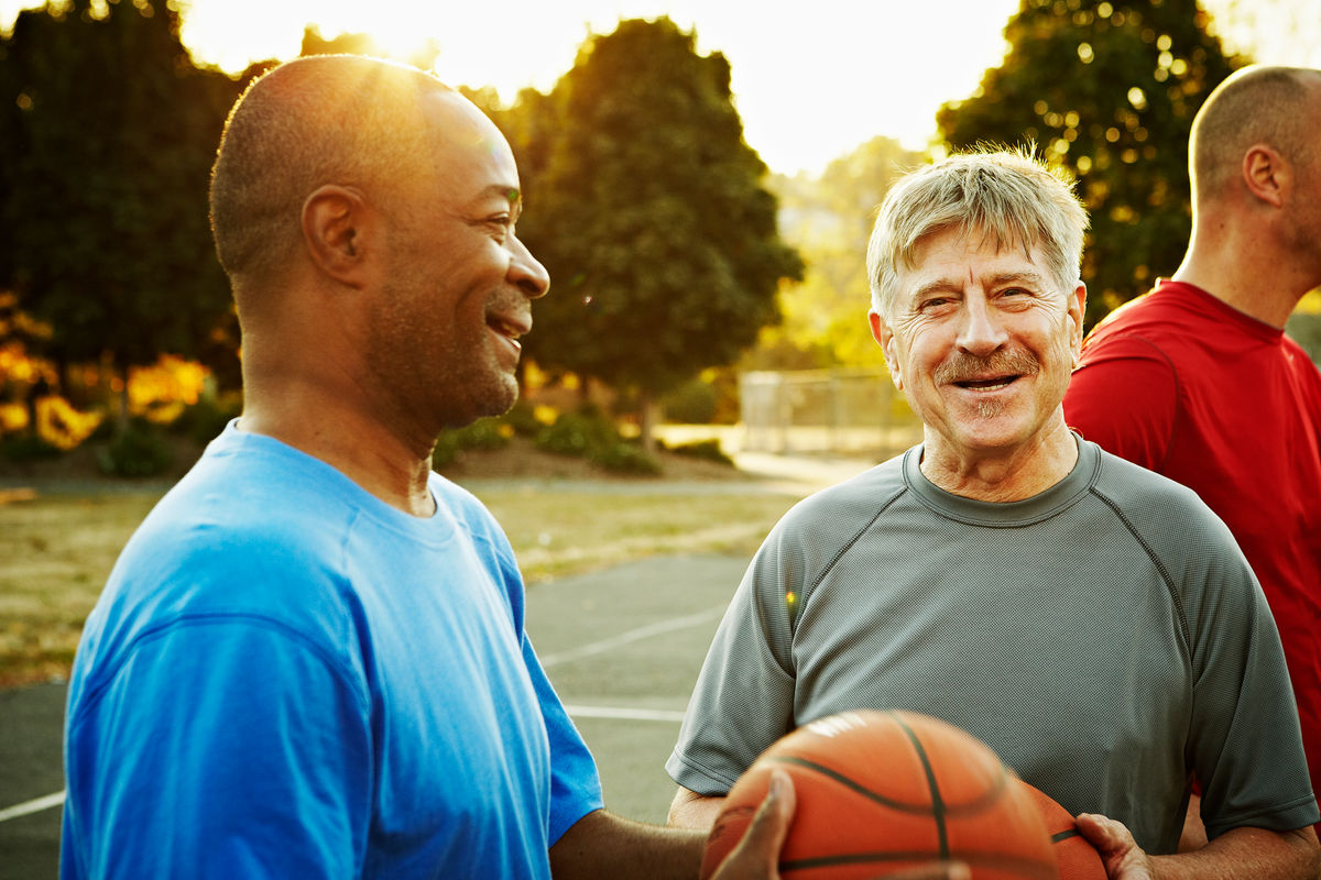 Group of older men playing a game of basketball in the evening