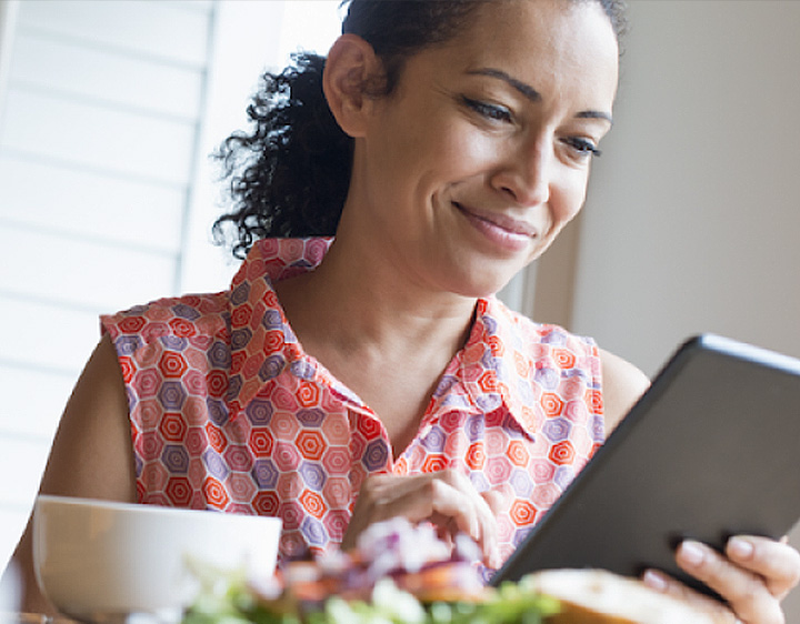 Woman looking at a tablet at her dining table
