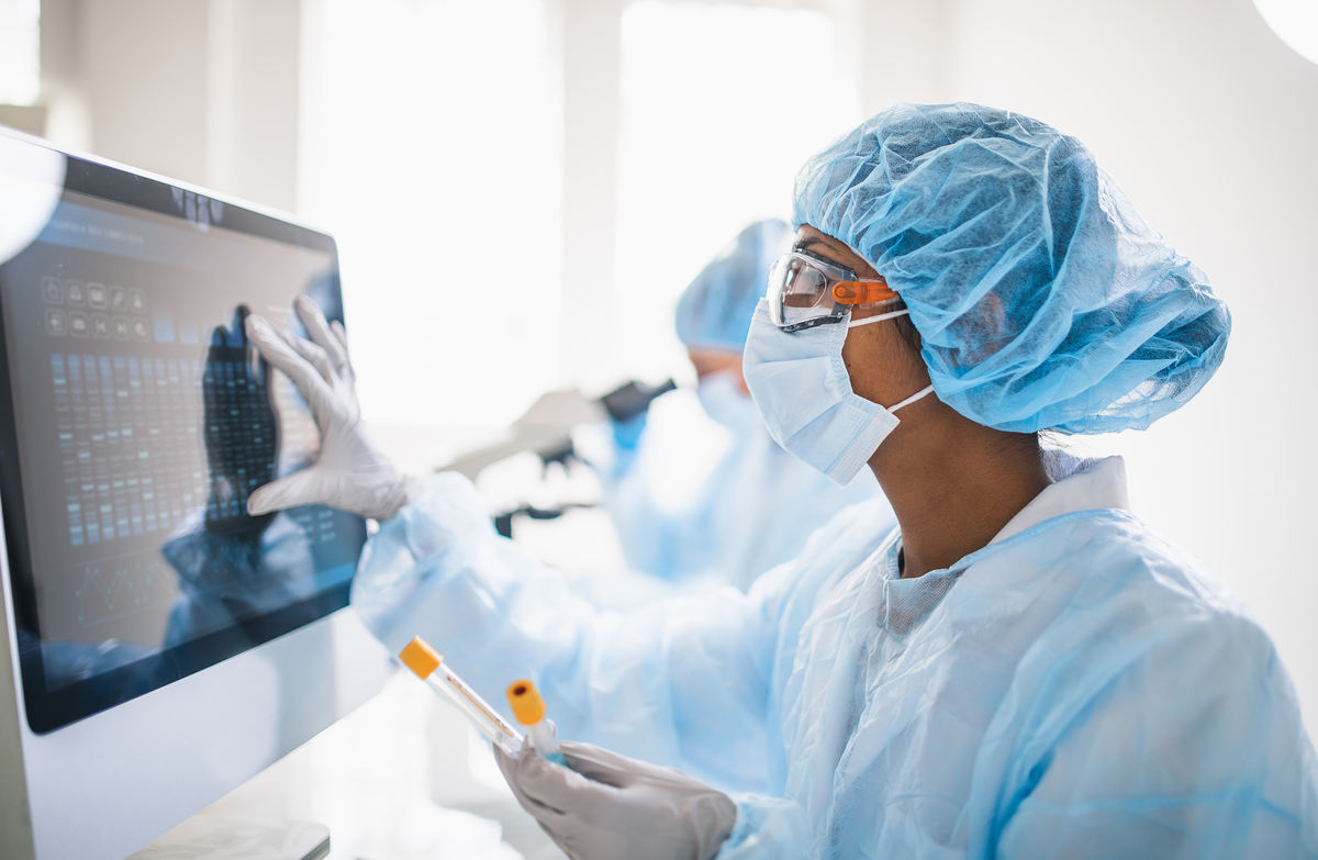 scientist in full PPE. They are zooming in on a screen to evaluate findings