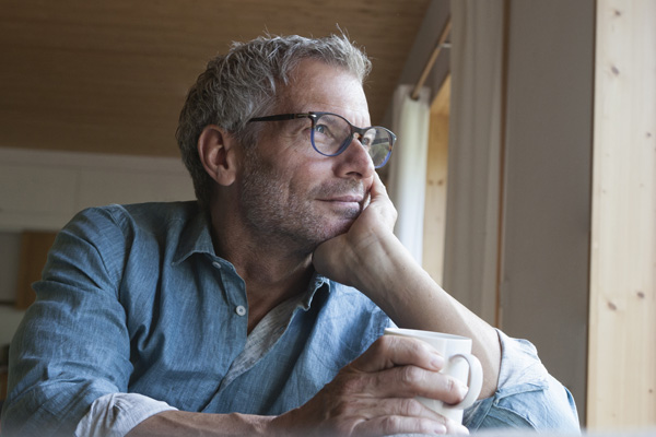 Middle aged man sitting at a table with a coffee mug in his hand