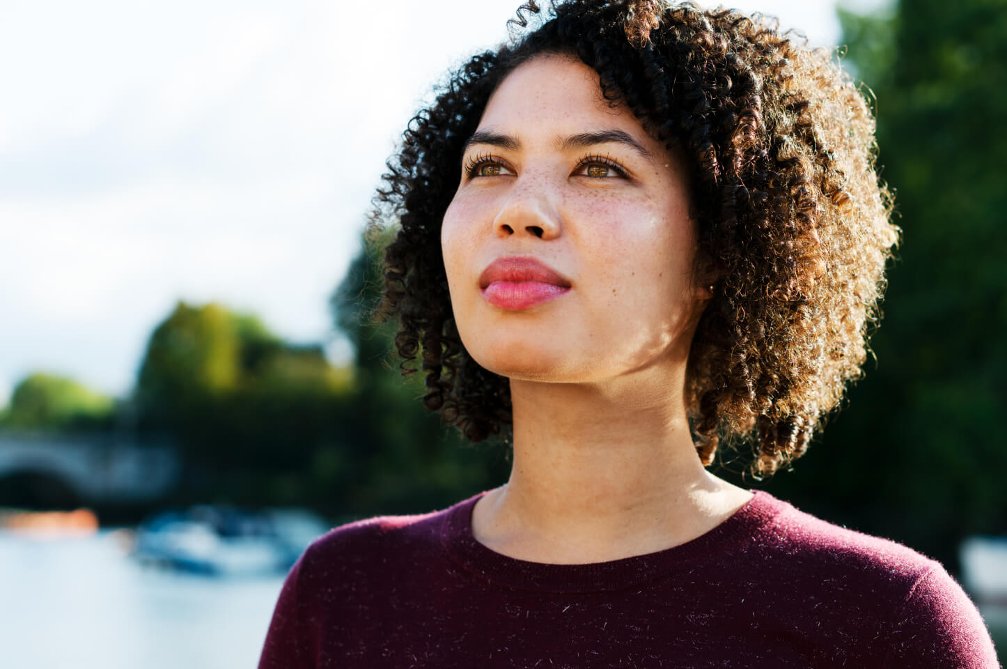 Woman standing outside. The sun is hitting her hair from behind