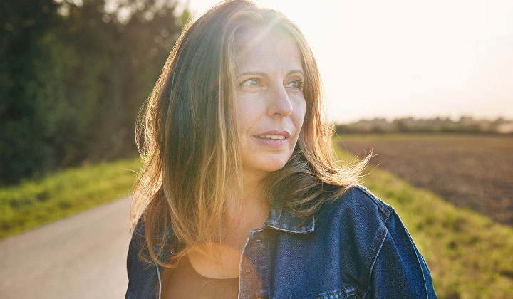 Woman standing in a road next to a field