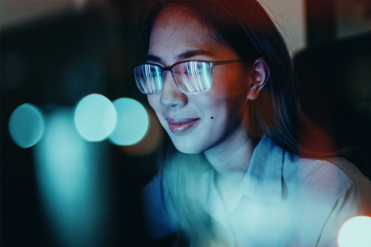 Woman wearing glasses while on a computer. There is a glare coming off the glasses