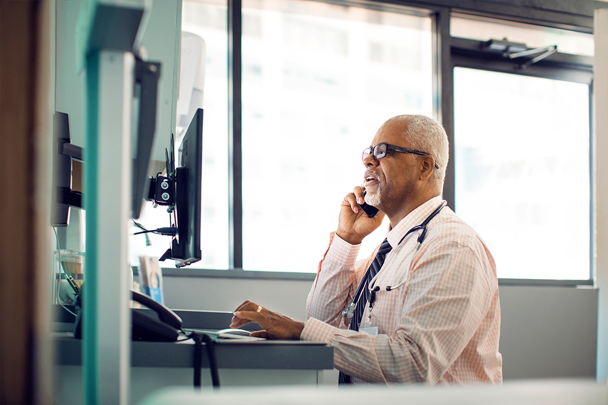 Provider sitting at a desk in front of a computer while on the phone