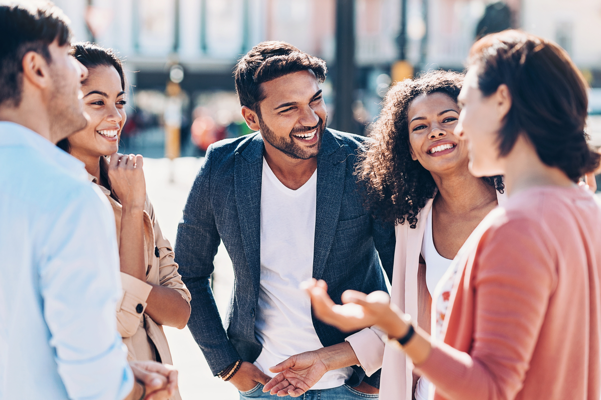 Group of five diverse friends stading in a link talking and laughing with each other