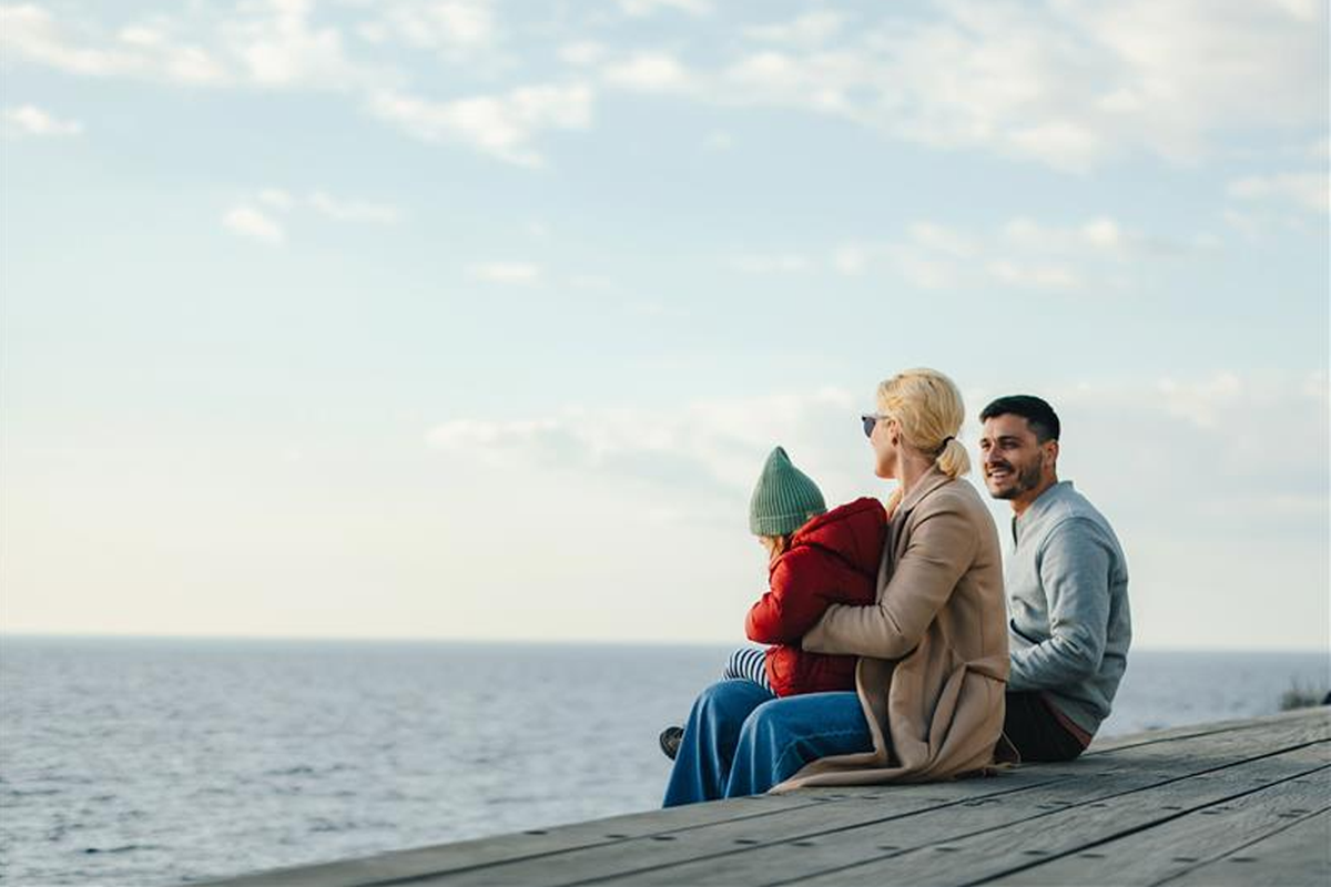 Family of three sitting on a dock