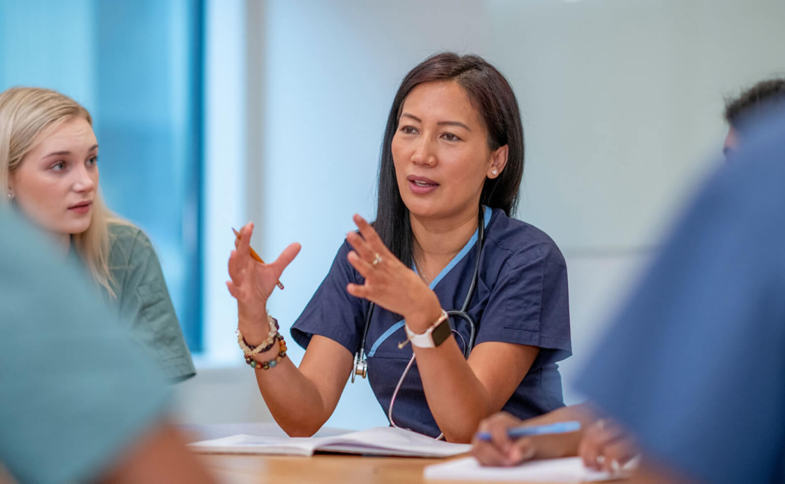 Provider sitting in a meeting with other providers. She is talking with her hands out