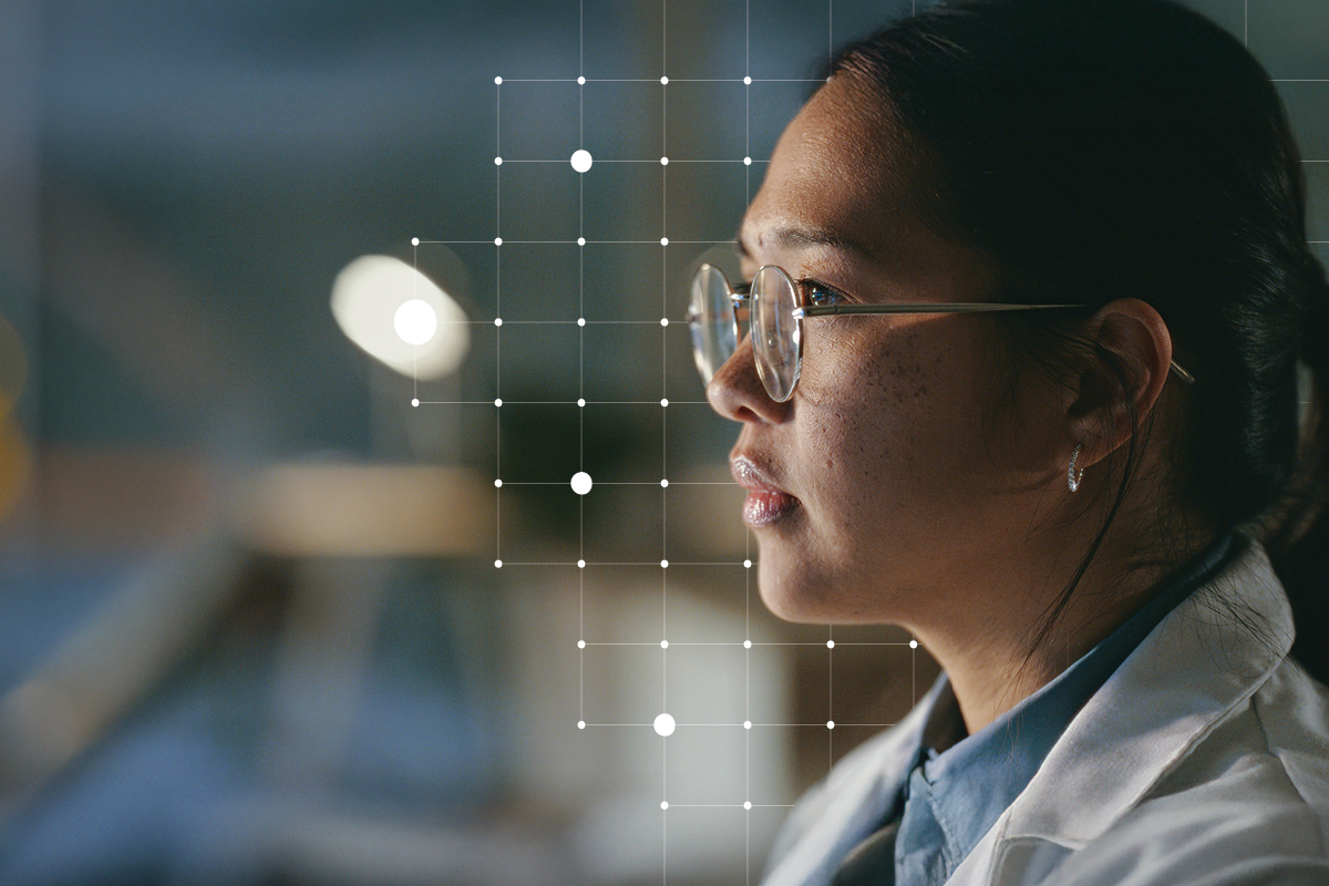 Scientist with glasses close up. It's dark with some lighting hitting her glasses. There are a grid of dots