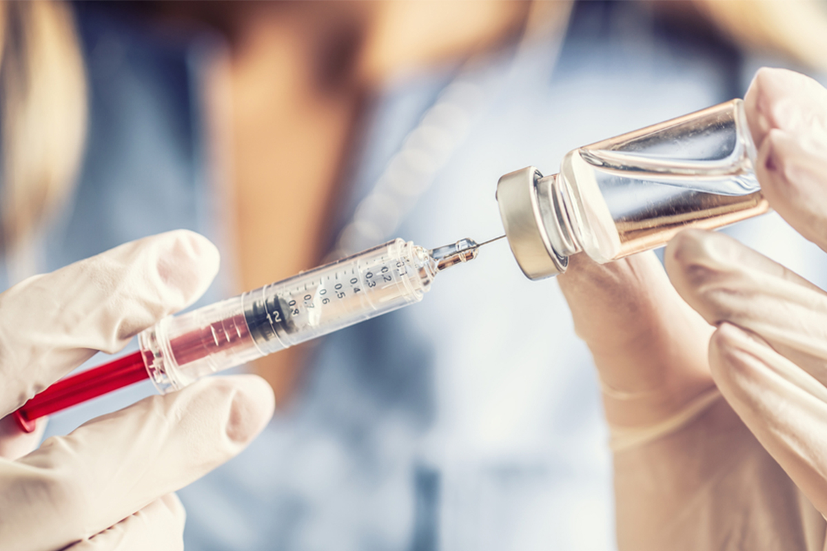 Proveedor extrayendo una vacuna de un vial con una aguja